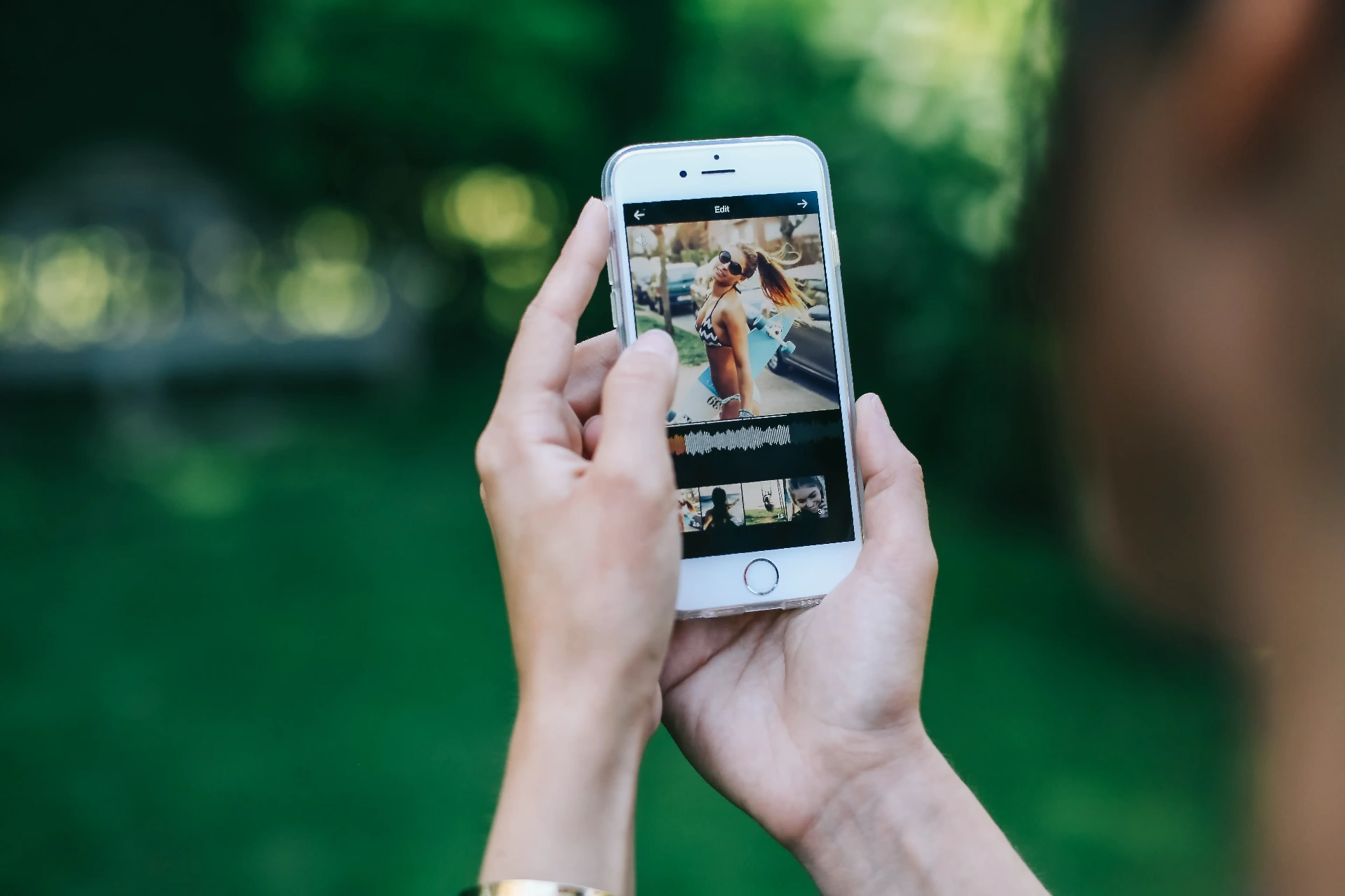 Socialmist music-video editor with waveform timeline on an iPhone held outdoors